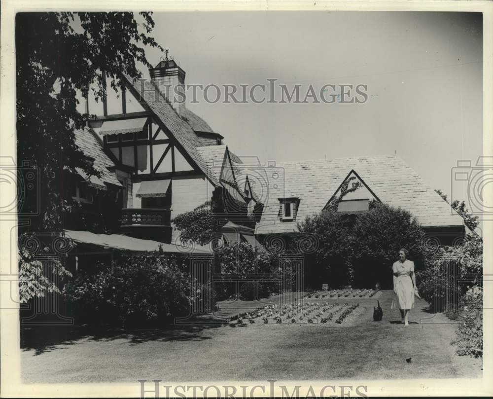 1940 Press Photo Unknown woman walking beside garden behind residence