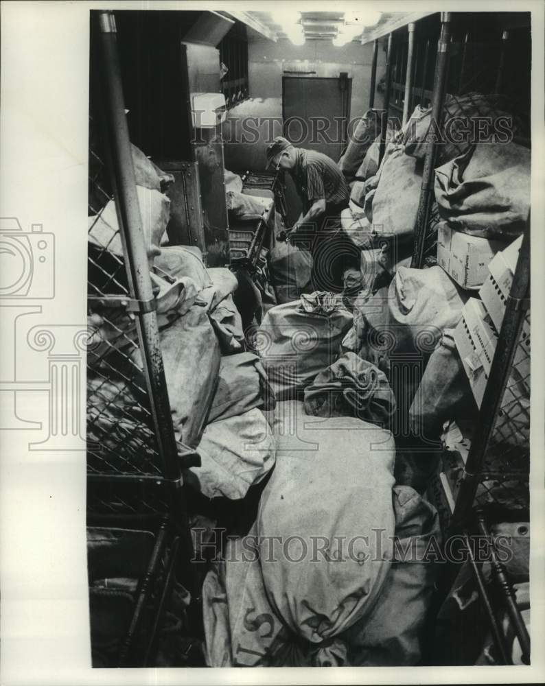 1965 Press Photo Mail Sorter George Schneider in room with mailbags, Milwaukee- Historic Images