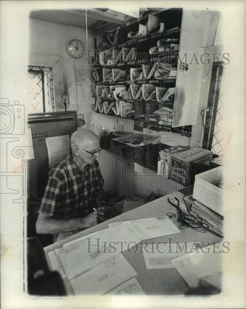 Load image into Gallery viewer, 1971 Press Photo Mr. Brown at his desk in post office waiting on customers
