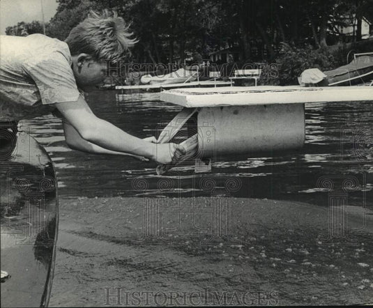 1964 Press Photo Joe stuffs mail into mailbox under diving board on lake.- Historic Images