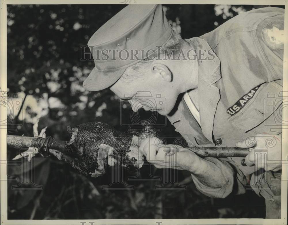 1957 Press Photo United States Army trainee inspects burned chicken on fire spit- Historic Images