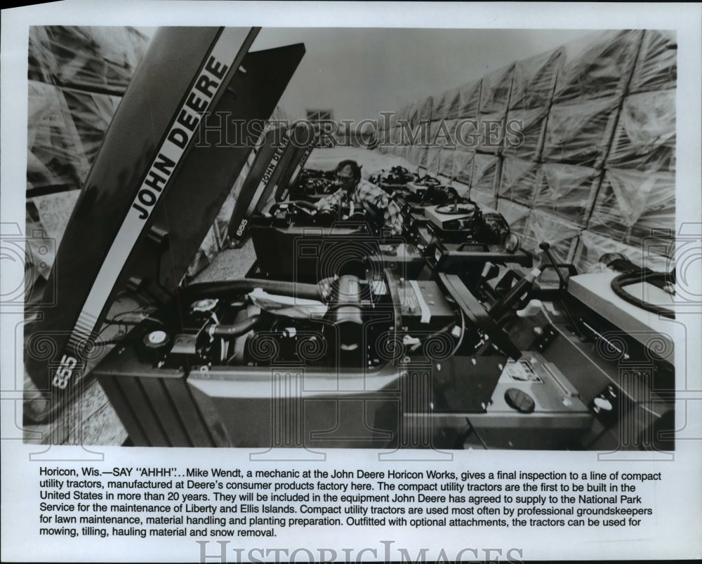 1986 Press Photo Mike Wendt inspects a line of utility tractors of John Deere- Historic Images