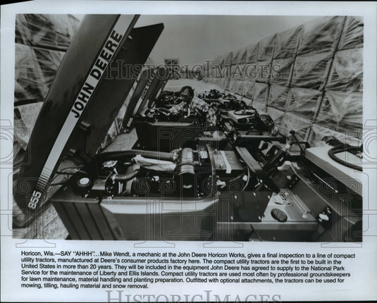 1986 Press Photo Mike Wendt inspects a line of utility tractors of John Deere- Historic Images