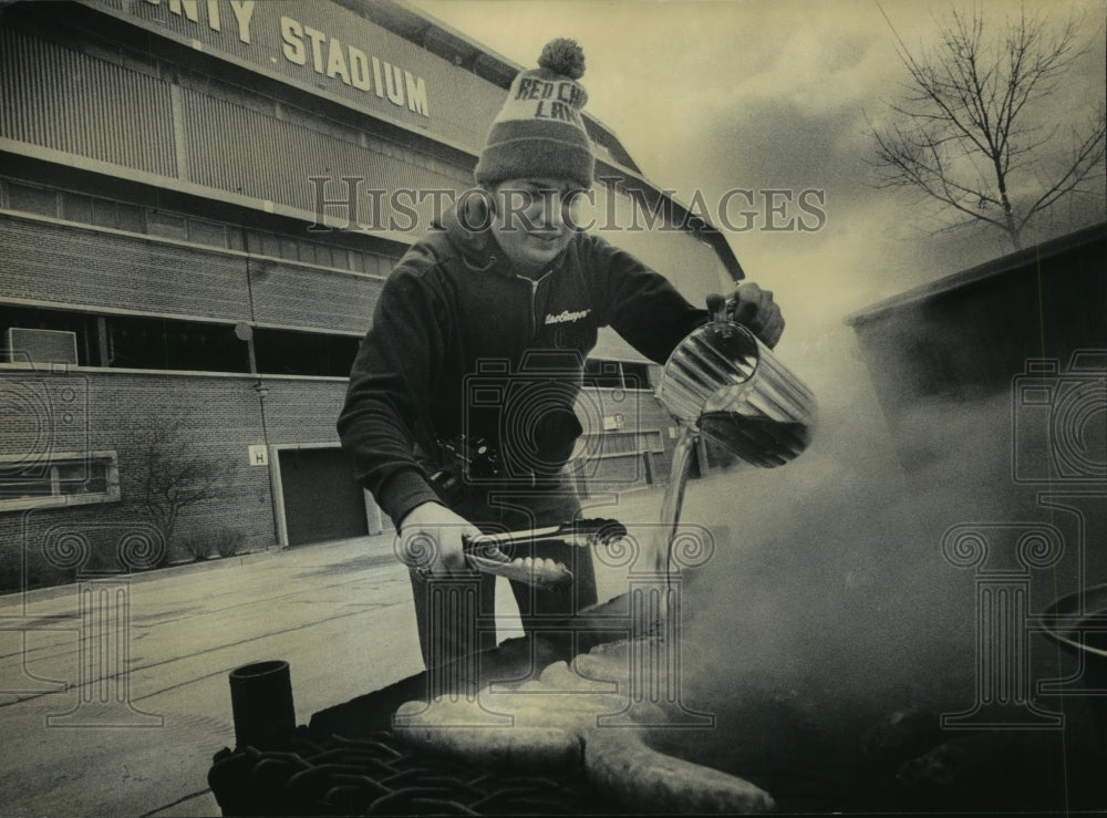 1983 Press Photo Brian Watkins poured beer over bratwurst at County Stadium.- Historic Images