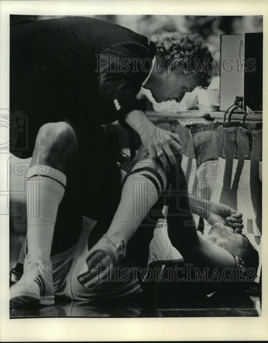 1984 Press Photo Basketball Trainer Jeff Snedeker Checks Marques Johnson's Knee- Historic Images