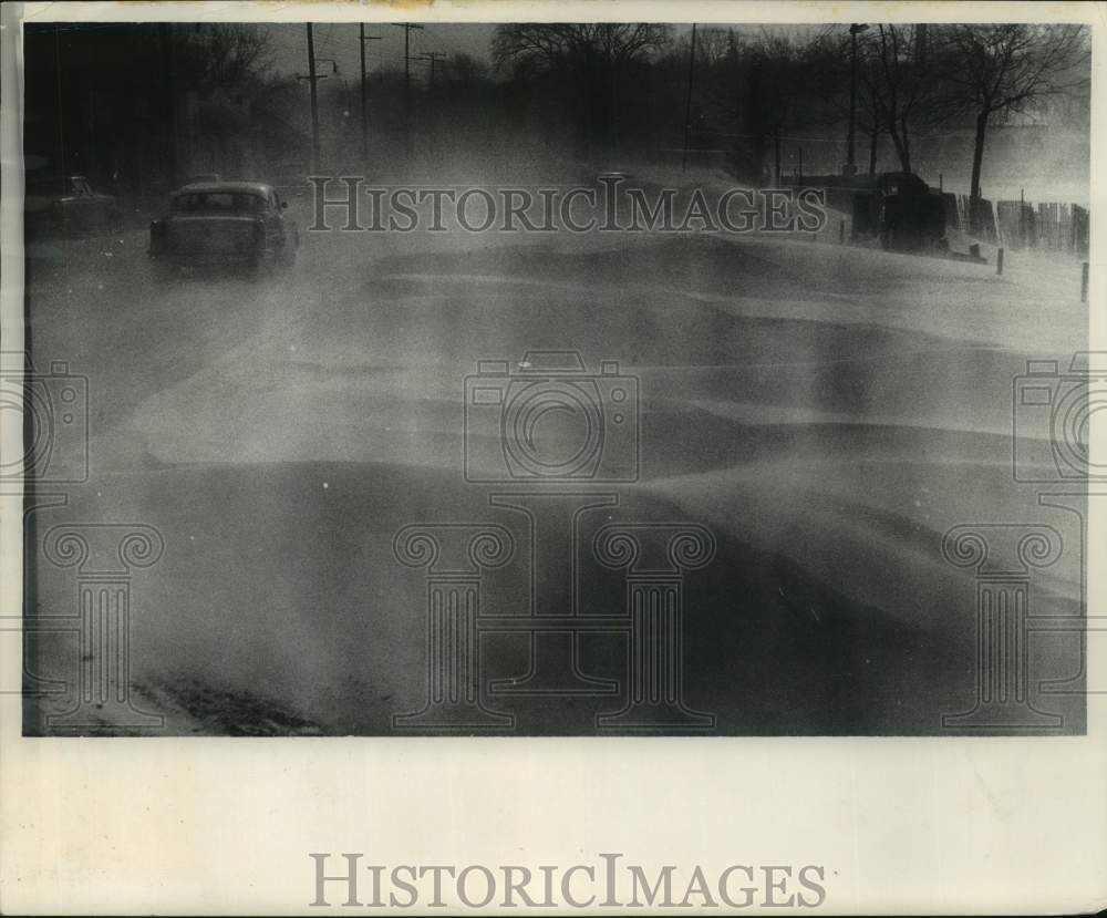 1964 Press Photo Snow whips across Pewaukee lake blocking traffic on nearby road- Historic Images