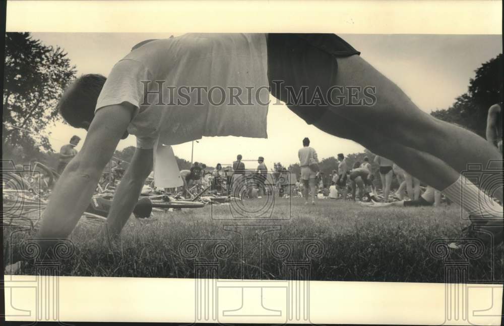 1987 Press Photo Nicholas Bandow stretched as others got ready for triathlon.- Historic Images