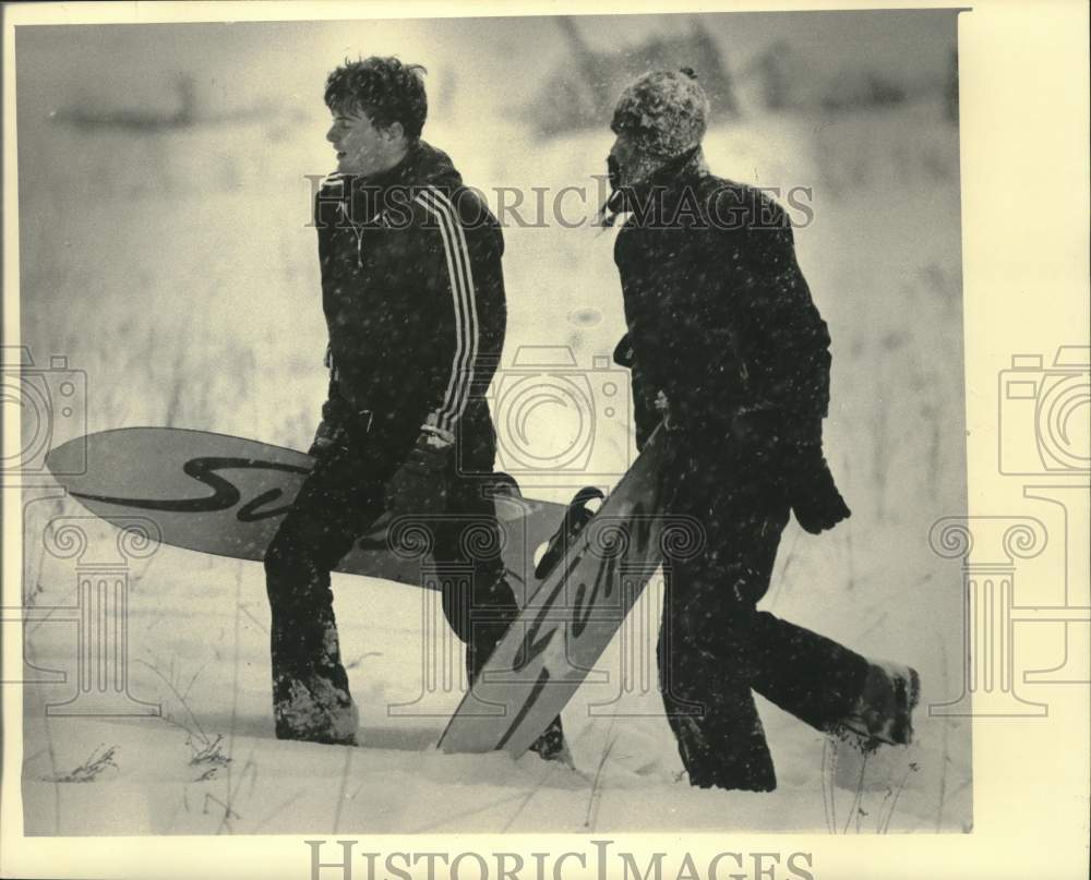 1986 Press Photo Sean McLaughlin and Kirk Johnson carrying their snow boards.- Historic Images