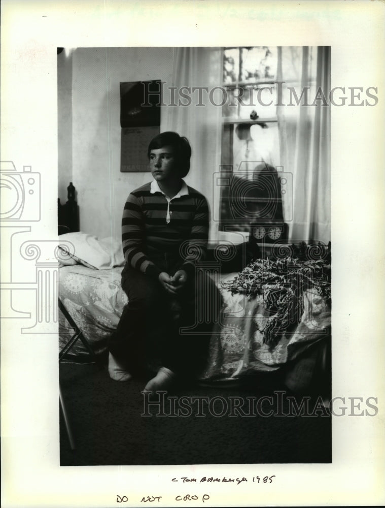 1986 Press Photo A youth sits quietly upon his bed photograph by Tom Bamberger