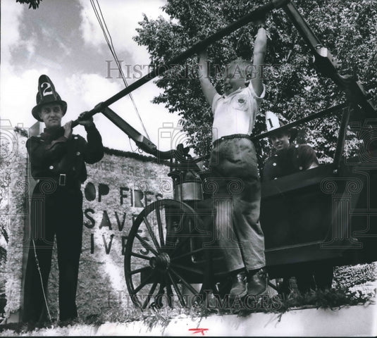 1958 Press Photo Donald Neldner hoisted himself on bar of a 1880 hand pumper.