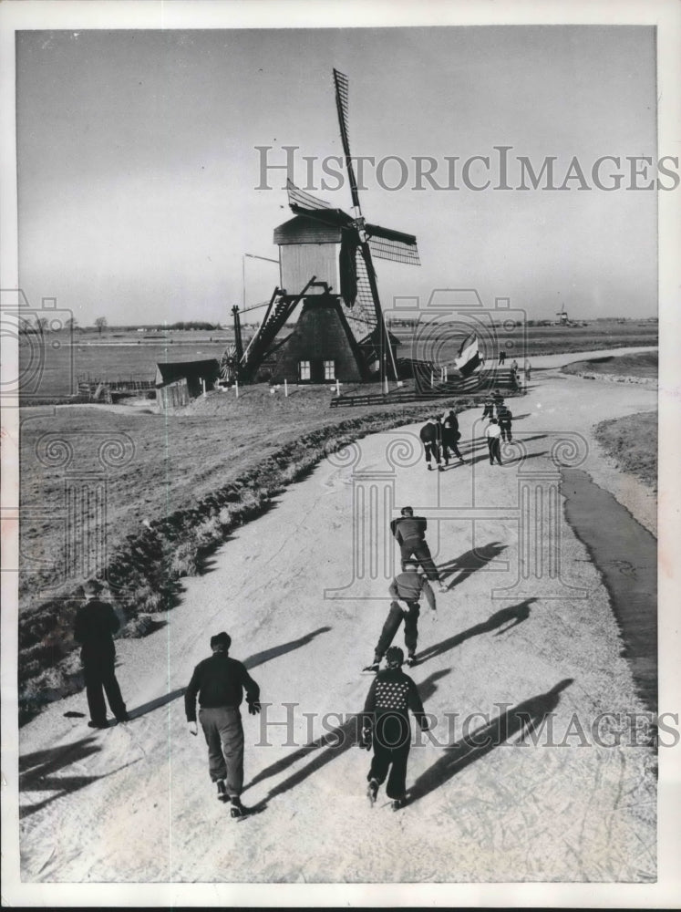 1956 Press Photo Skaters on frozen canal tour near Leiden, Holland windmill- Historic Images
