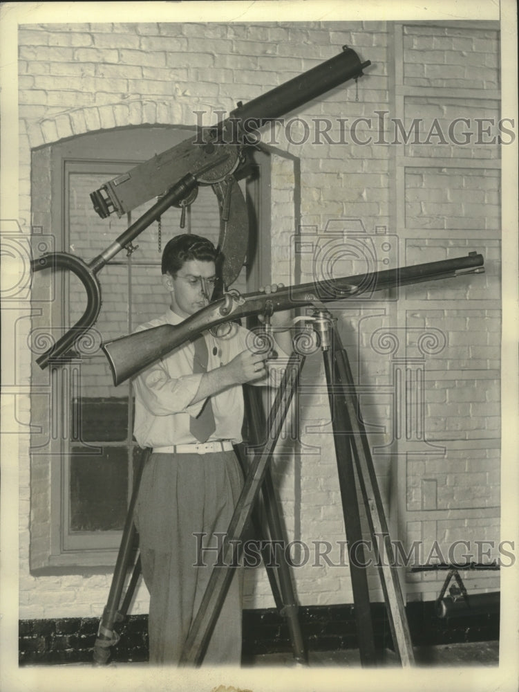 1940 Press Photo William Foy inspects a Harper&#39;s Ferry sniper&#39;s gun on tripod- Historic Images