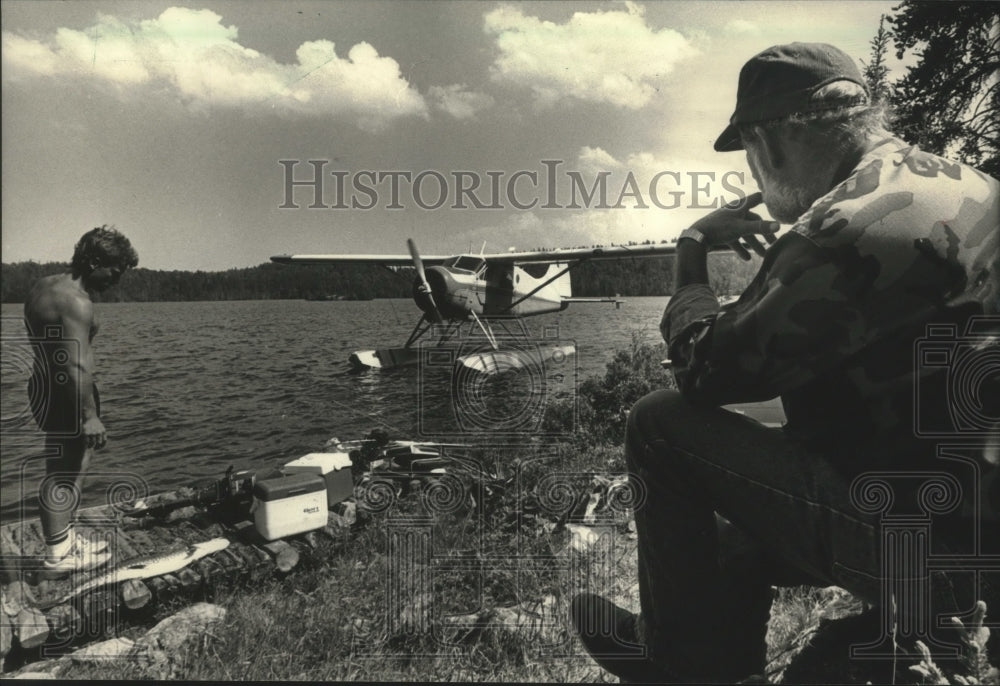 1988 Press Photo Fishermen-Rick Olynik and Jay Reed watch plane at Walmsley Lake- Historic Images