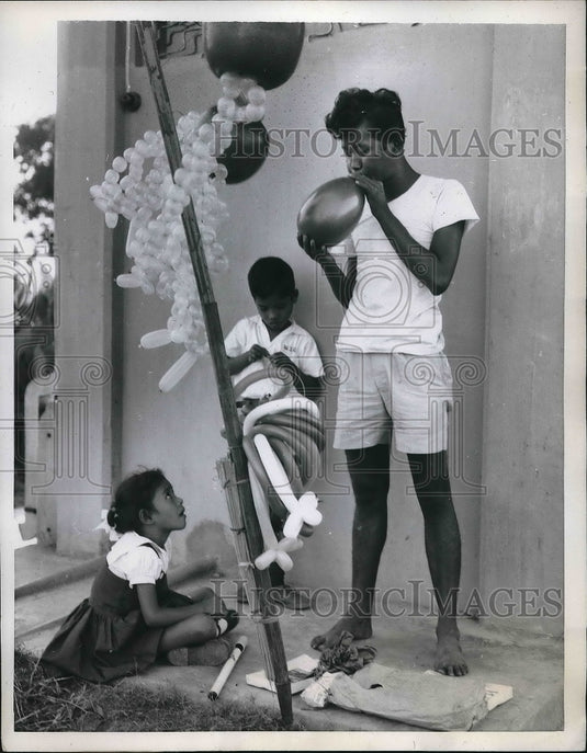 1959 Press Photo Girl watching boy blow up balloon in Bangkok Thailand- Historic Images