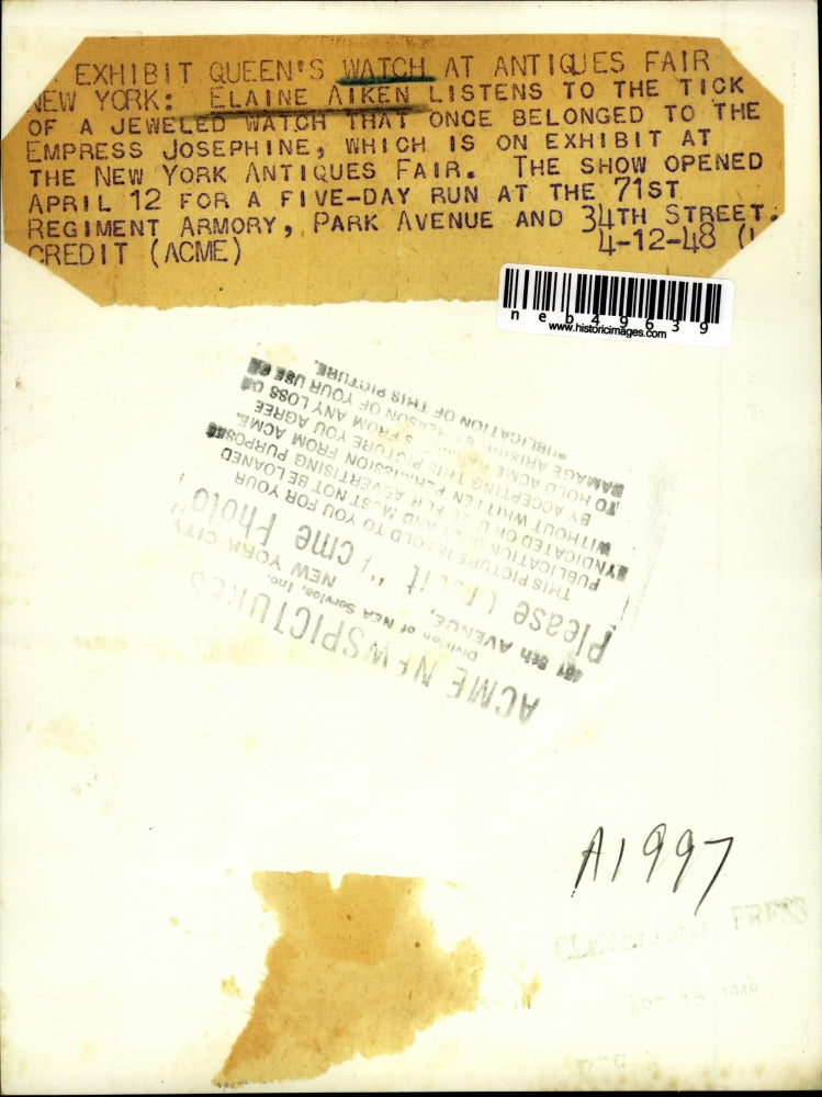 1948 Press Photo Elaine Aiken listening to watch at New York Antiques Fair