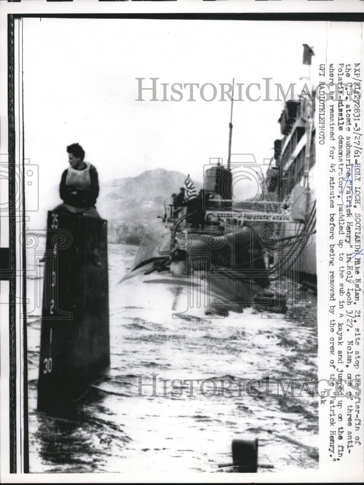 1961 Press Photo Mike Nelan sits on top of the after-fin of US atomic submarine