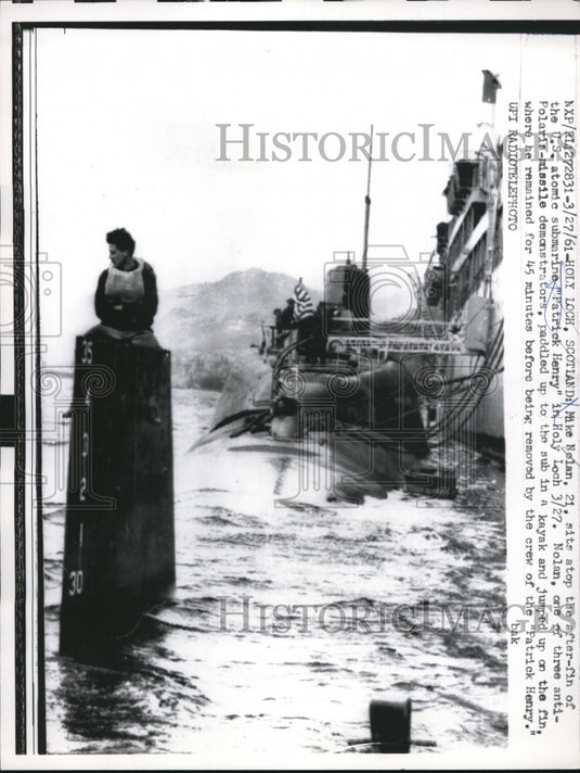 1961 Press Photo Mike Nelan sits on top of the after-fin of US atomic submarine
