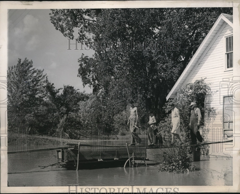 1947 Press Photo Fred Schneiter family walks across make-shift plank. flood.