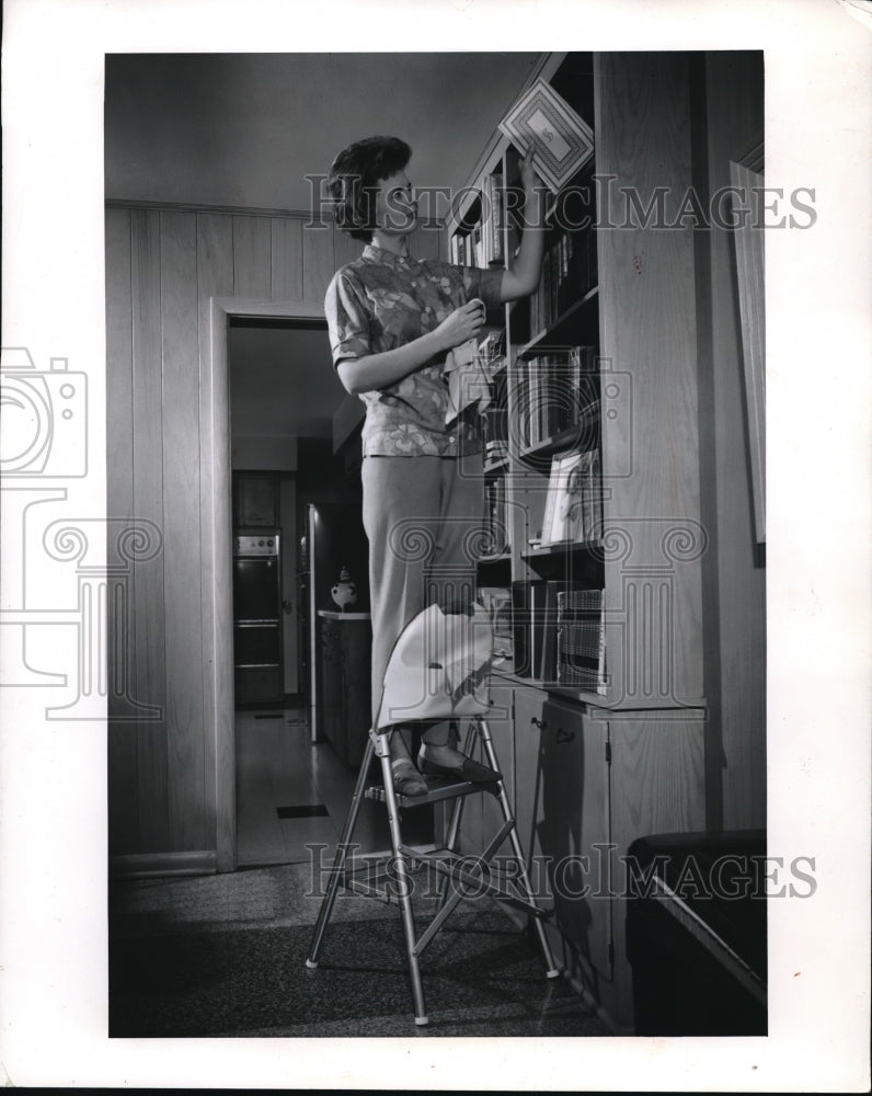 Load image into Gallery viewer, 1963 Press Photo Woman on Folding Stepladder Dusting Bookcase
