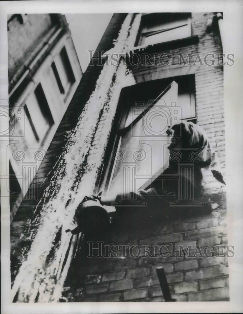 1947 Press Photo Kathleen Pike pours hot water on huge icicle on her building