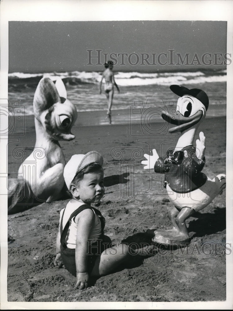 Load image into Gallery viewer, 1955 Press Photo Italian Toddler Ettore Basevi On Beach With Cartoon Characters
