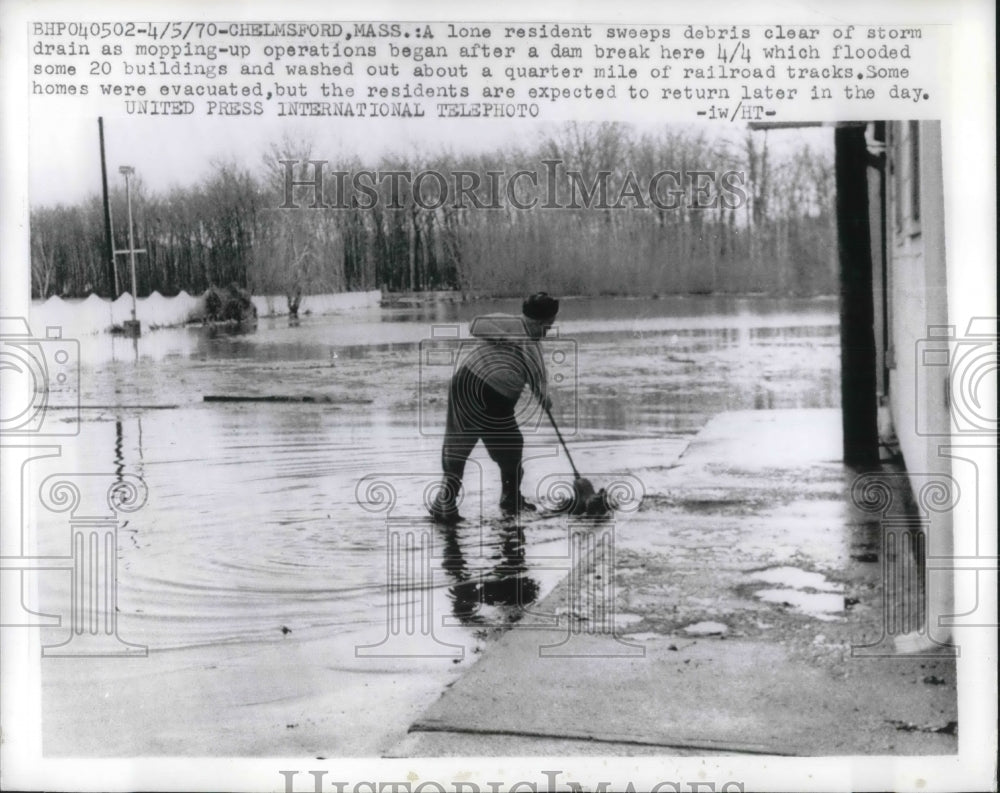 1970 Press Photo A resident sweeping the water away after a storm.