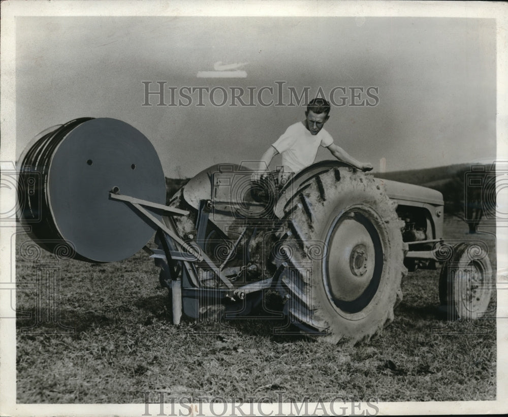 1955 Press Photo Farmer Stands With Pipe Layer Tractor Hitch