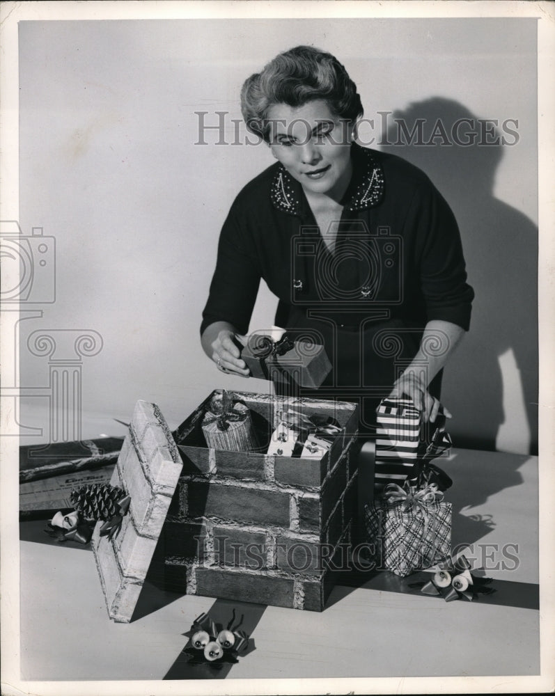 1955 Press Photo Woman Puts Christmas Gifts In Box - nec63914