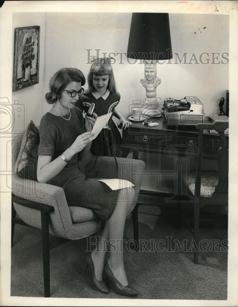 Press Photo A woman and child at their home listen to recording machine
