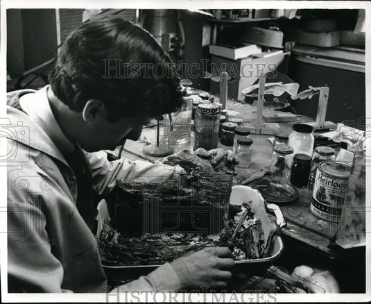 1969 Press Photo Lab Technician Raymond Mendez gently hammers a pine tree log