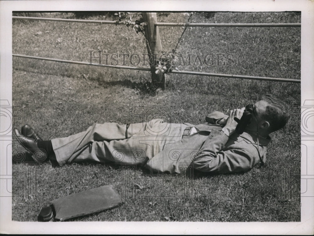 1937 Press Photo Man lays in the grass to take a photograph - nec71382