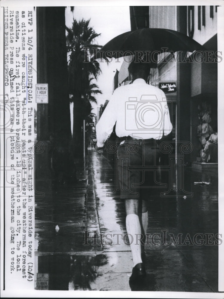 1956 Press Photo Riverside, Calif man walking in rain when forecast was sunny