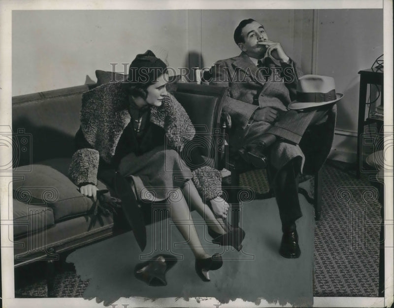 Load image into Gallery viewer, 1938 Press Photo Man &amp; woman as he doesn't help with rain gear - nec72751
