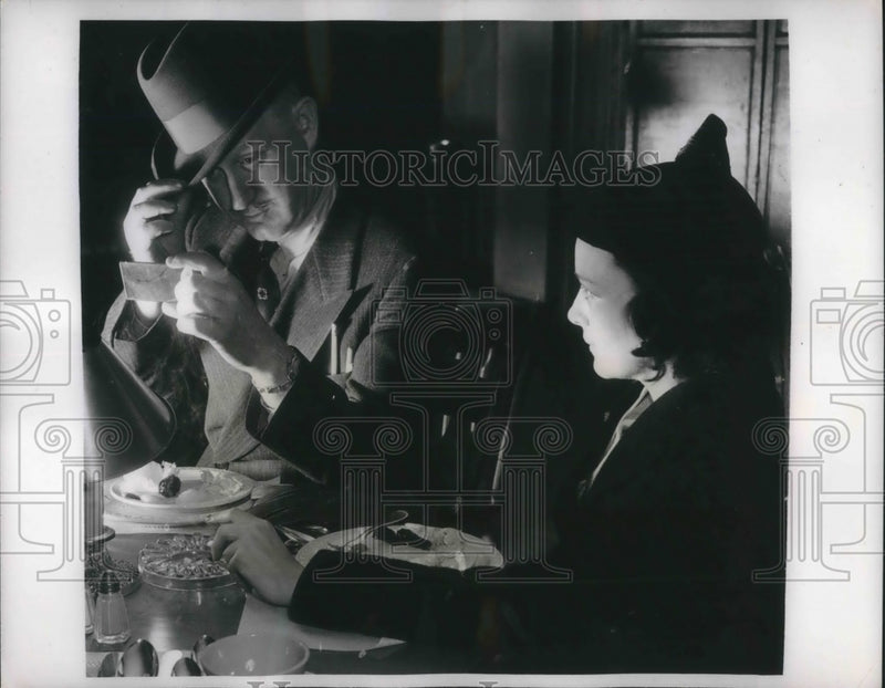 Load image into Gallery viewer, 1938 Press Photo Man &amp; woman &amp; dinner table, wearing his hat at a rakish angle

