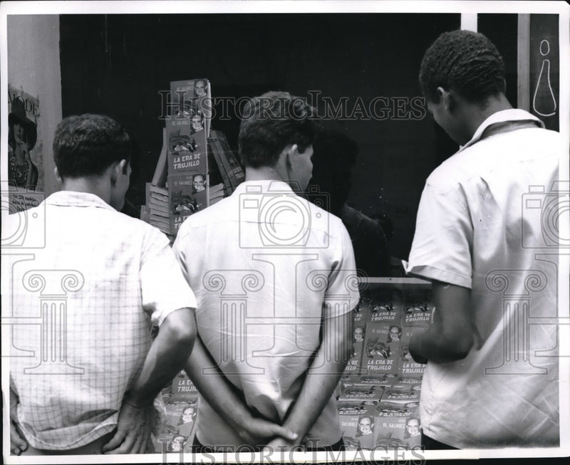 Load image into Gallery viewer, 1962 Press Photo Bominicans look at book in store window
