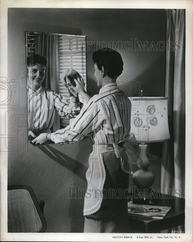1962 Press Photo A woman cleaning a mirror at her home