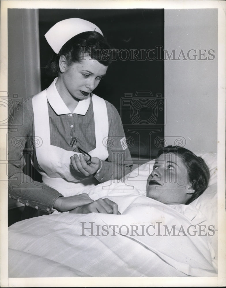 1950 Press Photo An atractive young nurse takes the pulse of her patient