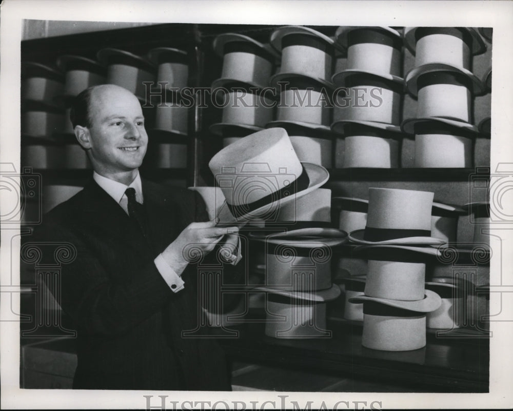 1939 Press Photo A man holding England Toppers for men in a shop