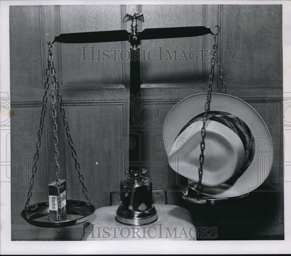 1956 Media Photo Cigarette on left & hat on right of the balance scale