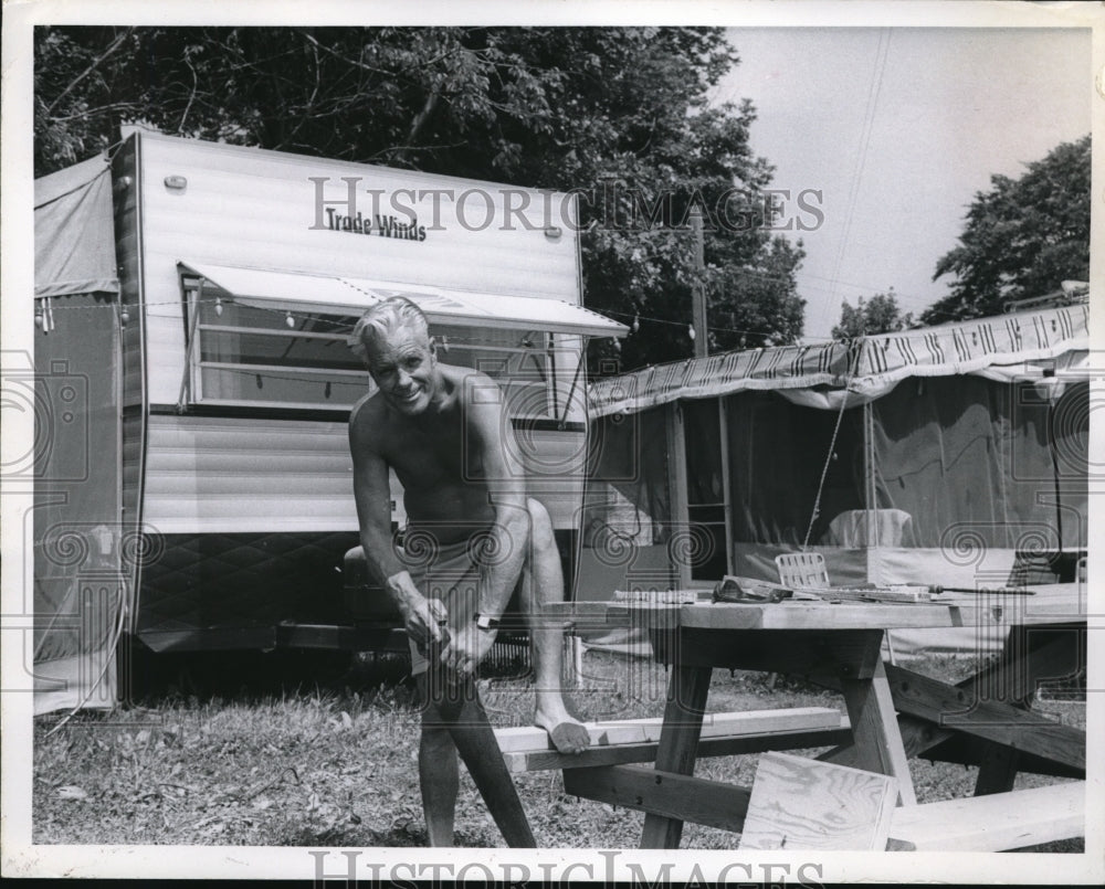 Press Photo Man Cutting Wood at his Campsite