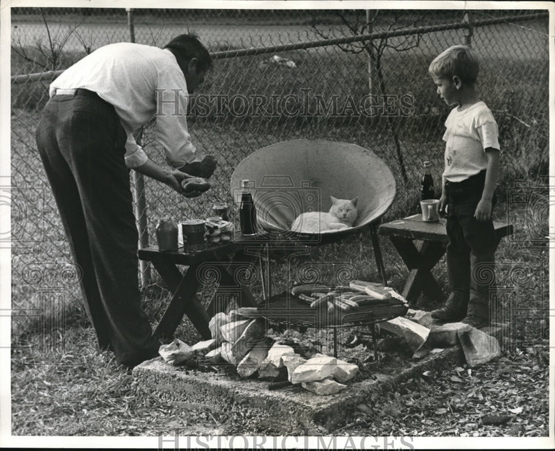 Load image into Gallery viewer, 1961 Press Photo Tex Taylor and son, Joe, do backyard cookout

