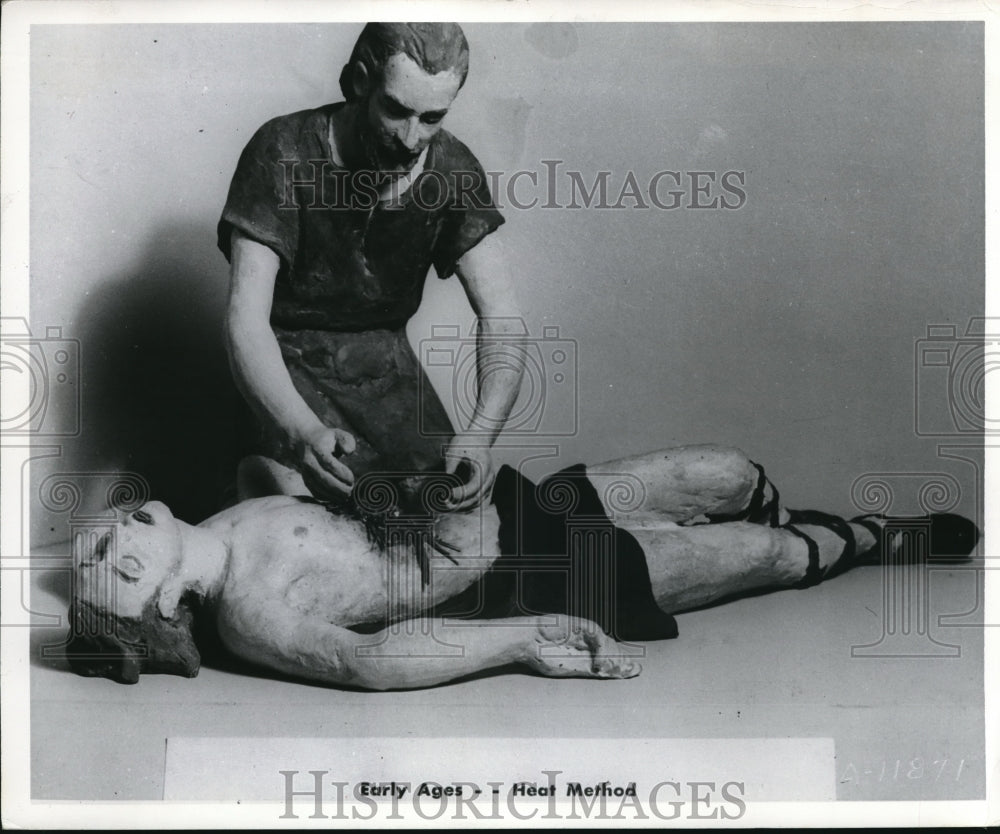 1958 Press Photo Man demonstrates early ages heat method treatment