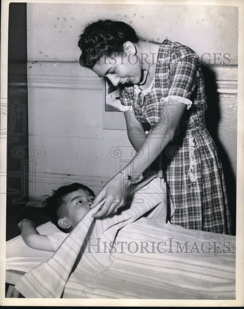 Load image into Gallery viewer, 1945 Press Photo Roger Vehara being tucked in for nap by Jeanne Immarim.
