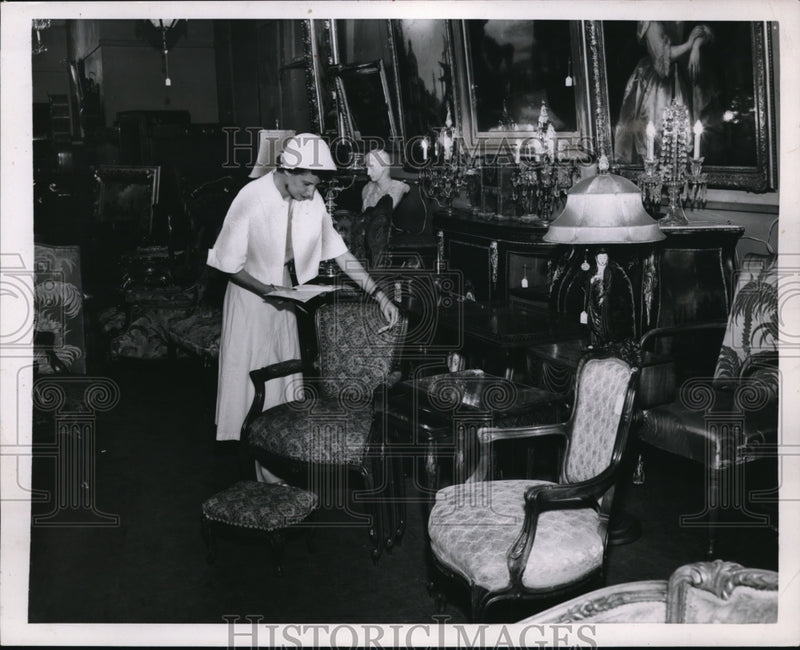Load image into Gallery viewer, 1953 Press Photo A woman bargain hunting furniture at a auction
