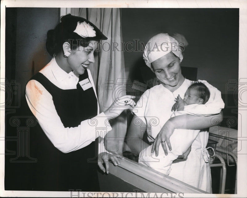 Load image into Gallery viewer, 1957 Press Photo Mrs. Colombo plays with the baby carried by Nurse Perdo
