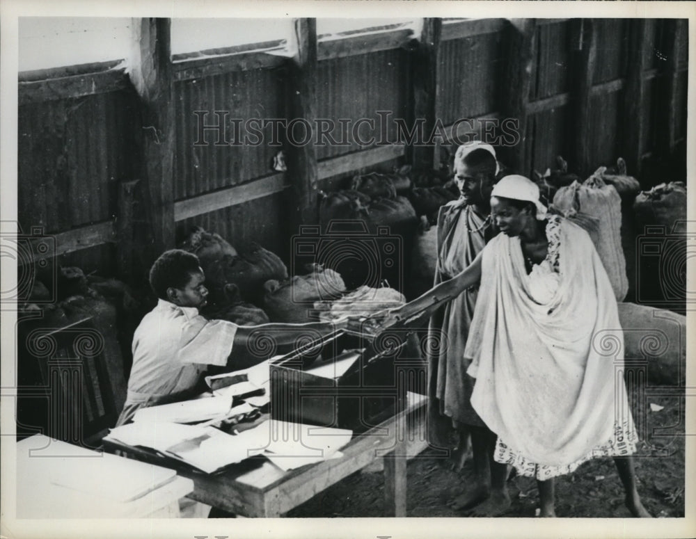1962 Press Photo Two Kikuyu Villagers paying their fines to a Kenya official.