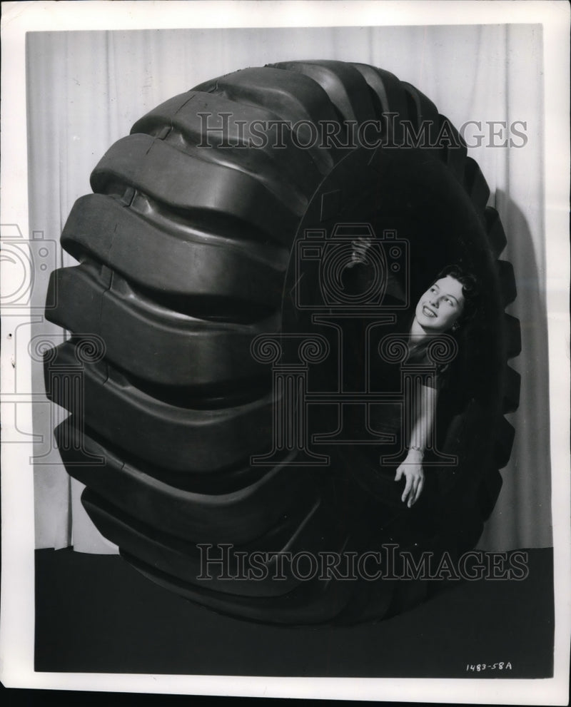 Load image into Gallery viewer, 1958 Press Photo Elaine Jordaan poses in a Goodyear off road truck tire
