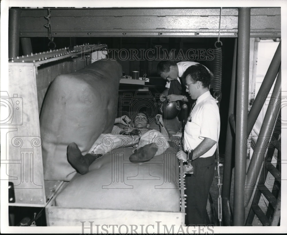 1964 Press Photo technician lies between to latex airbags prior to vibration