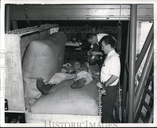 1964 Press Photo technician lies between to latex airbags prior to vibration