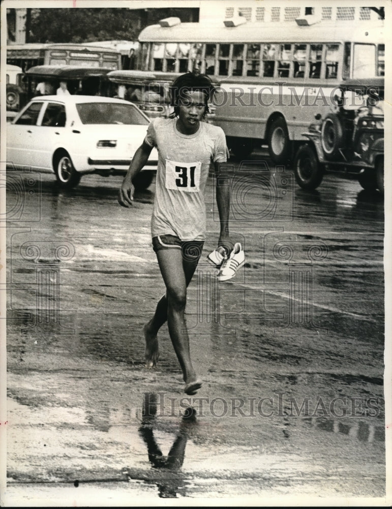 Load image into Gallery viewer, 1975 Press Photo Runner Carries Shoes In 12 Mile Race Because They're Too Costly
